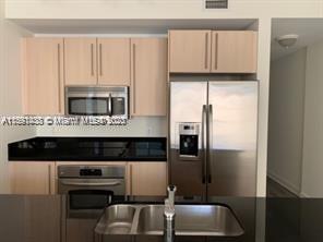 1111 Southwest 1st Avenue, Unit 2316N Miami, FL 33130 - Photo 6 of 37 a kitchen with cabinets and stainless steel appliances