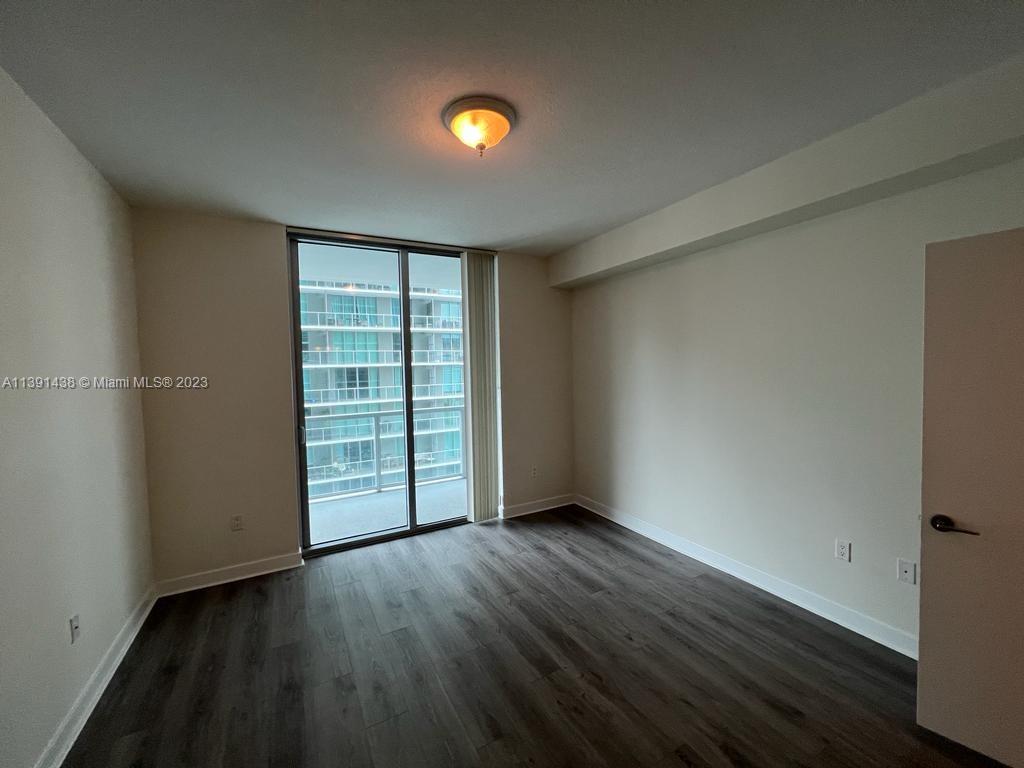 1111 Southwest 1st Avenue, Unit 2316N Miami, FL 33130 - Photo 9 of 37 an empty room with wooden floor closet and windows