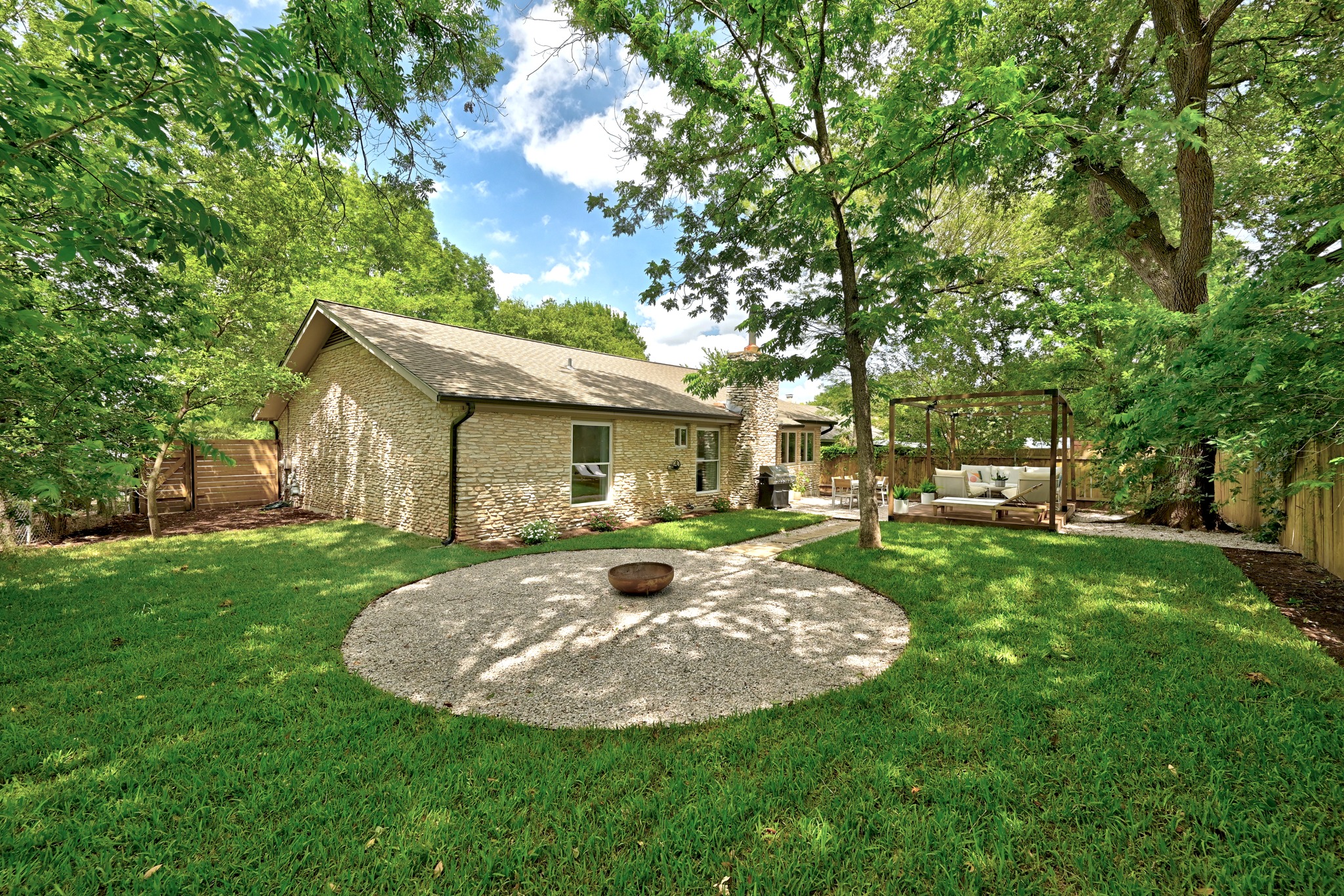 7110 Windrift Way Austin, TX 78745 - Photo 28 of 30 A private, verdant backyard sanctuary with a fire pit, patio, and lush mature trees.