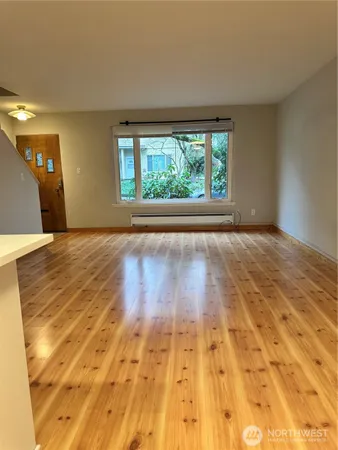 a view of an empty room with wooden floor and a window