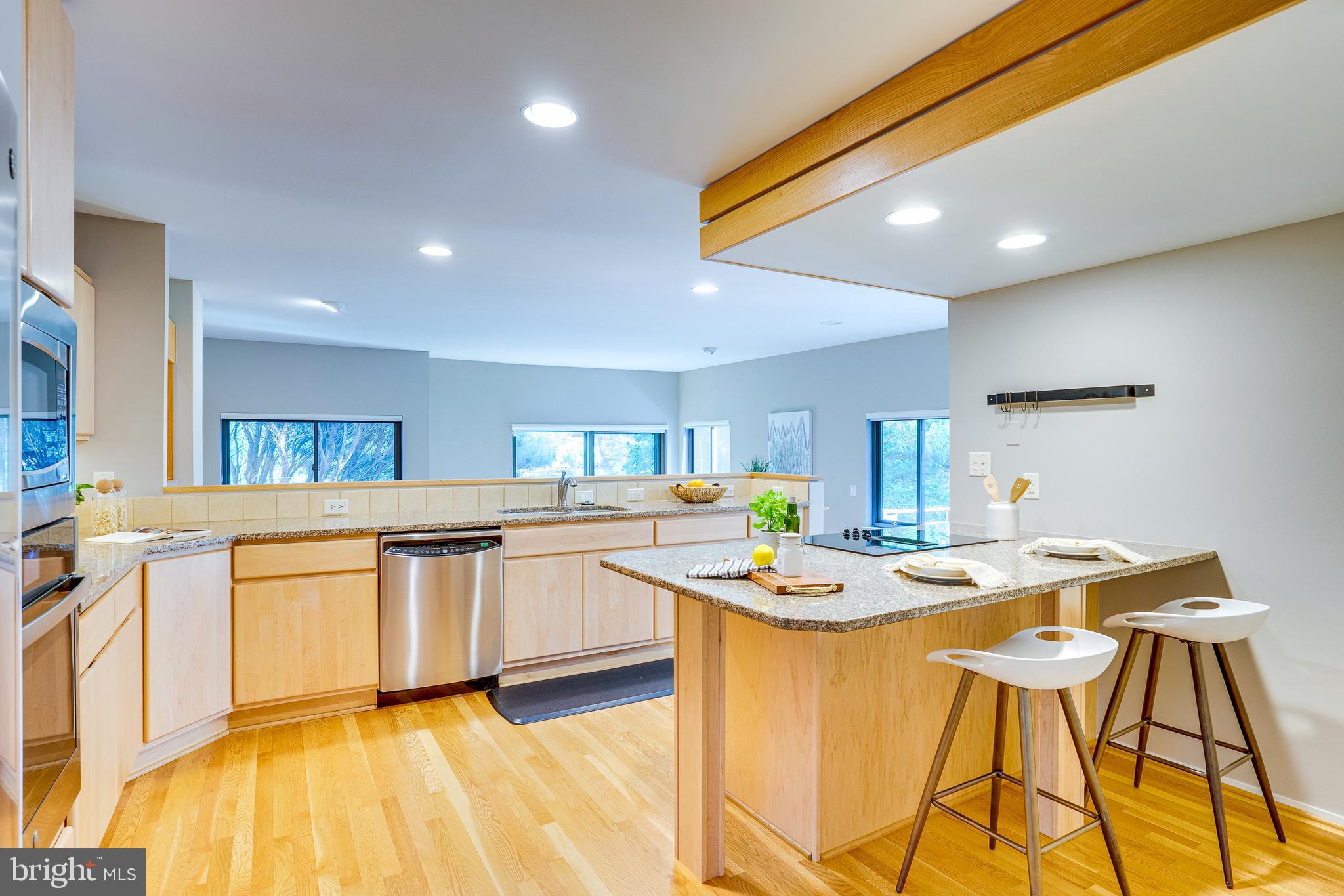 2148 South Bay Lane Reston, VA 20191 - Photo 37 of 73 a kitchen with stainless steel appliances granite countertop a kitchen island a stove a sink dishwasher and white cabinets with wooden floor