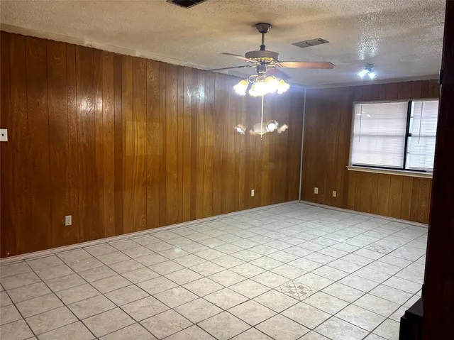 a view of an empty room and chandelier fan