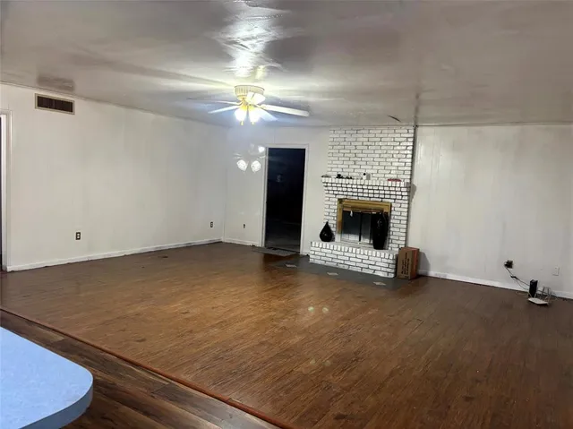 an empty room with fireplace and chandelier fan