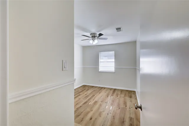 an empty room with a window and a ceiling fan