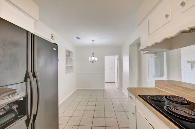 a view of a refrigerator in kitchen and white cabinets