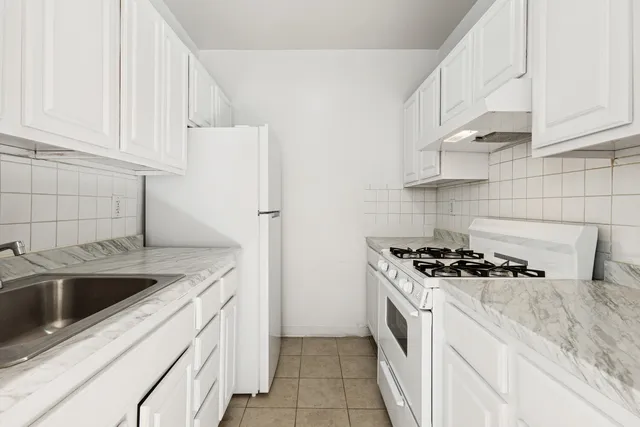 a kitchen with granite countertop a sink stove and refrigerator