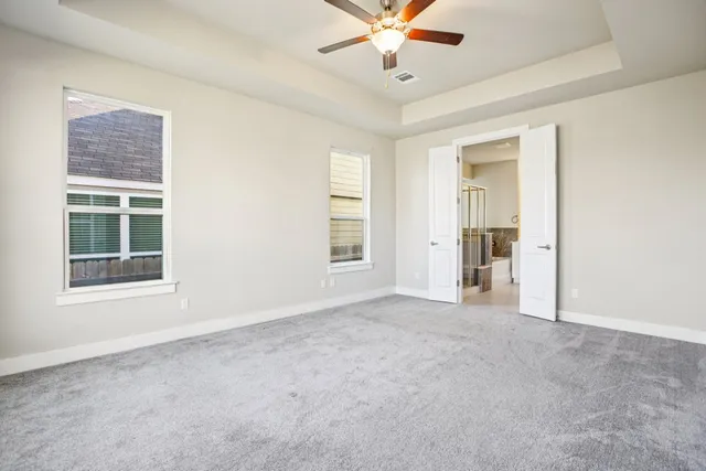 an empty room with windows and fan