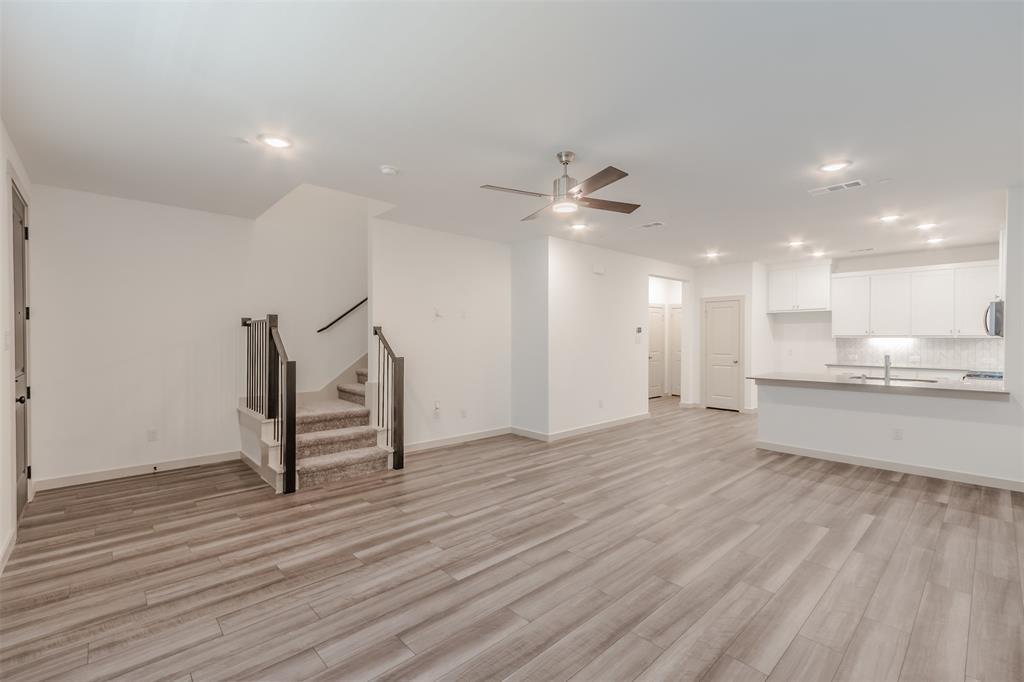 682 Vista Oaks Road Lewisville, TX 75067 - Photo 15 of 38 a view of an empty room with wooden floor and a kitchen