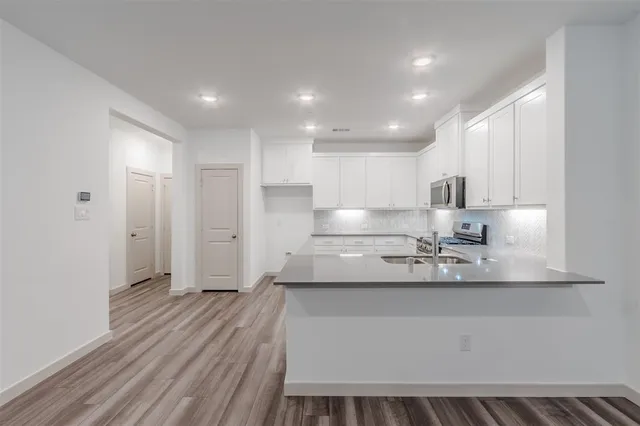 a large kitchen with kitchen island a stove a sink dishwasher and a refrigerator with wooden floor