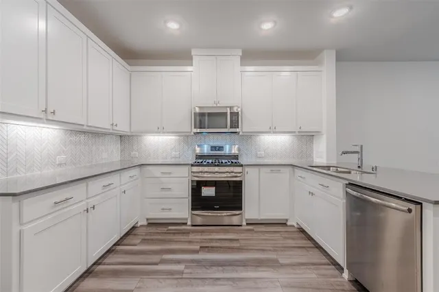 a kitchen with granite countertop white cabinets and stainless steel appliances