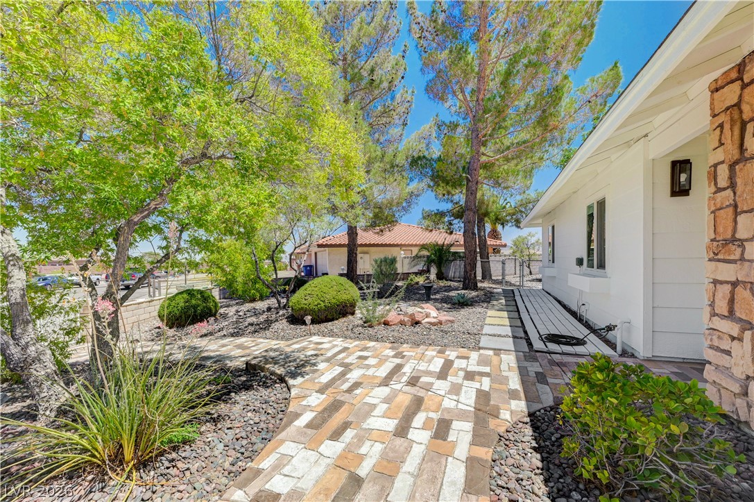 7631 Bermuda Road Las Vegas, NV 89123 - Photo 7 of 64 A winding brick pathway guides visitors through lush landscaping to a charming residence.