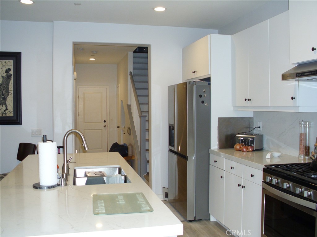 27393 Red Rock Road Moreno Valley, CA 92555 - Photo 4 of 31 a kitchen with refrigerator a stove a sink and white cabinets