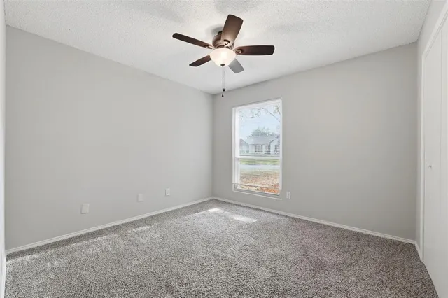 an empty room with a ceiling fan and window