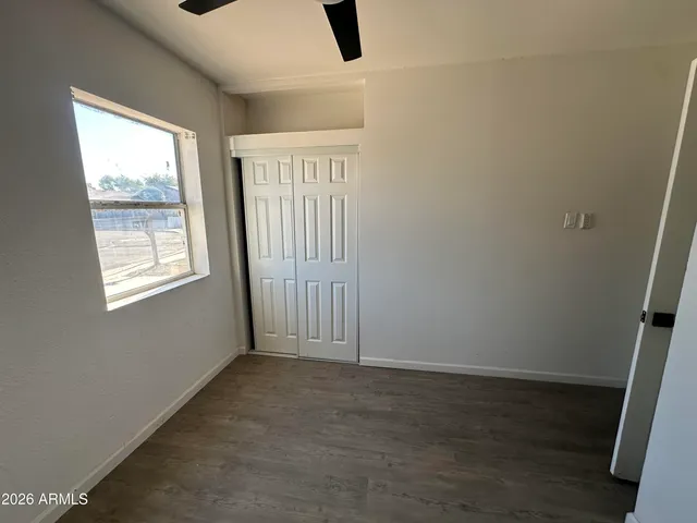an empty room with wooden floor fan and windows