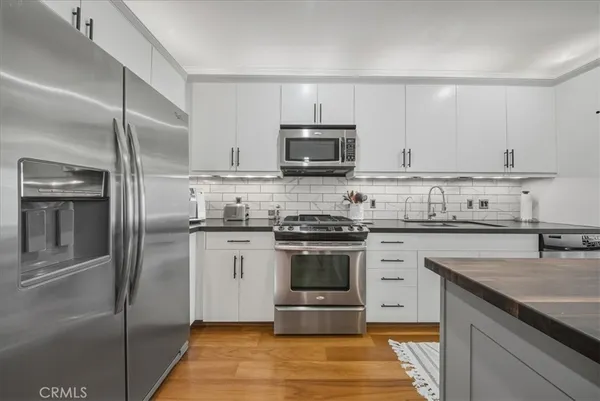 a kitchen with a sink stainless steel appliances and wooden floor