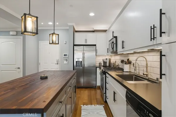 a kitchen with kitchen island a counter top space a sink stainless steel appliances and cabinets