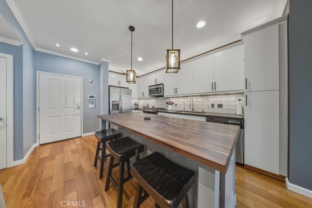 1901 Victoria Avenue, Unit 116 Oxnard, CA 93035 - Photo 6 of 31 a kitchen with kitchen island a wooden floor and white cabinets