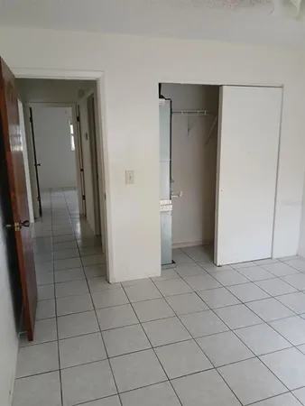 a view of a refrigerator in kitchen and an empty room in wooden floor