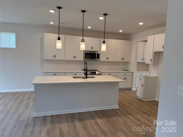 a view of a kitchen with kitchen island a sink wooden floor and glass window