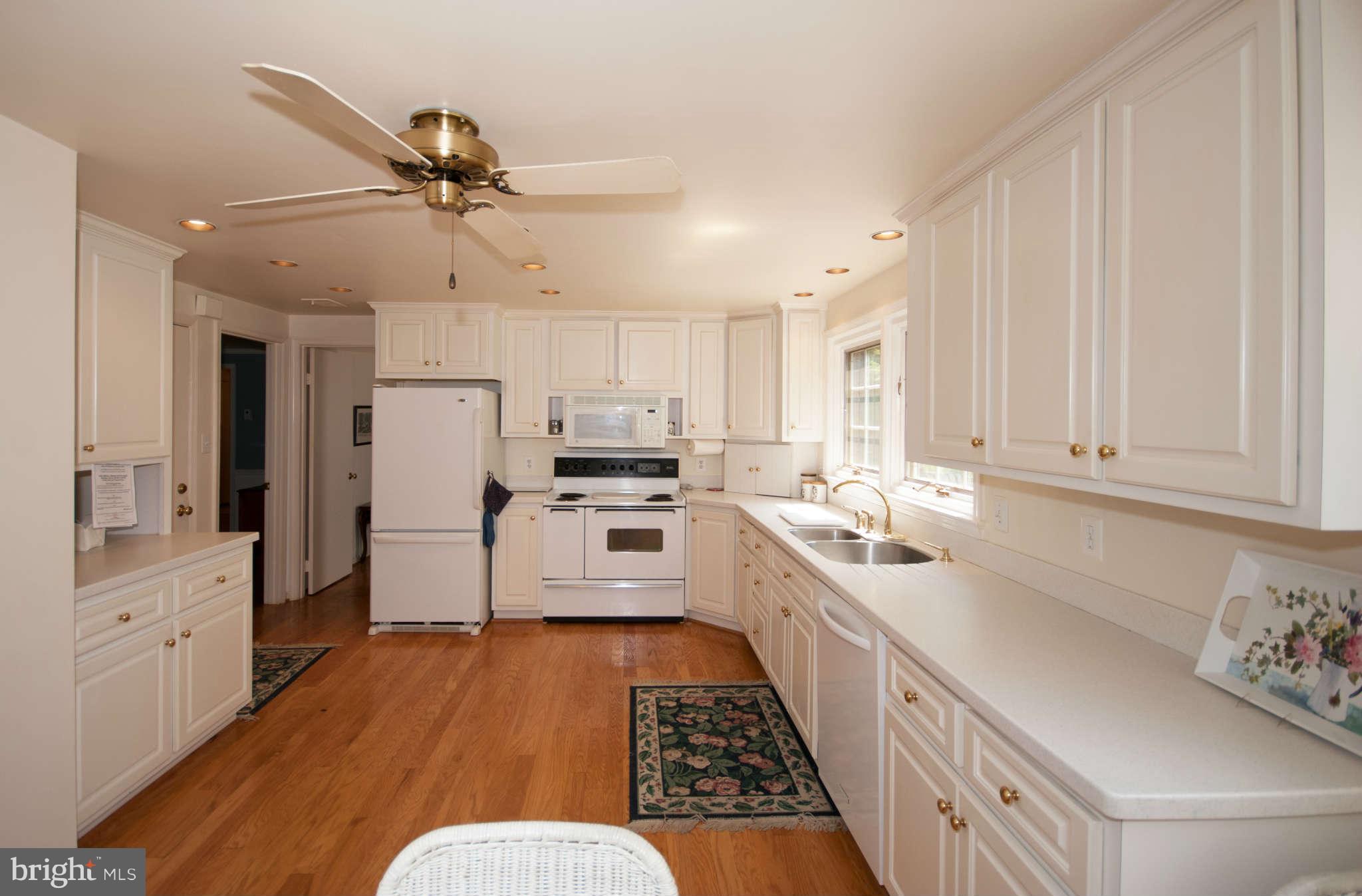 12433 Over Ridge Road Potomac, MD 20854 - Photo 6 of 30 a kitchen with stainless steel appliances a refrigerator a sink dishwasher a stove and white cabinets with wooden floor