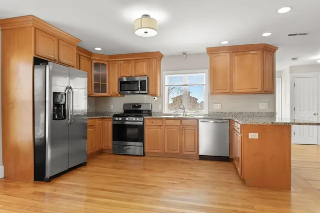 a large kitchen with stainless steel appliances granite countertop a refrigerator and a stove top oven