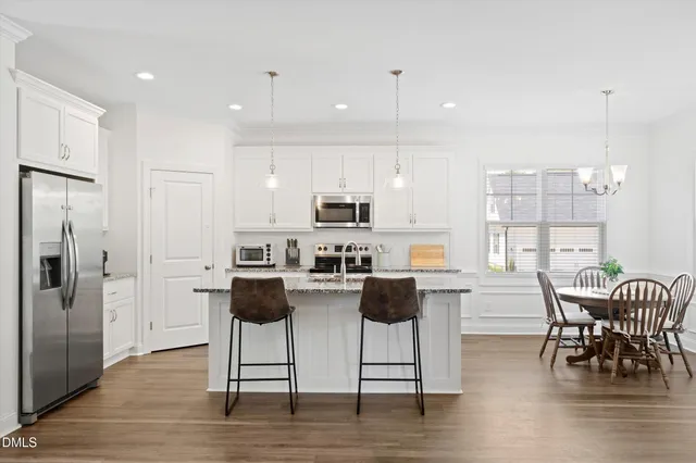 a kitchen with stainless steel appliances kitchen island granite countertop a dining table chairs and granite counter tops