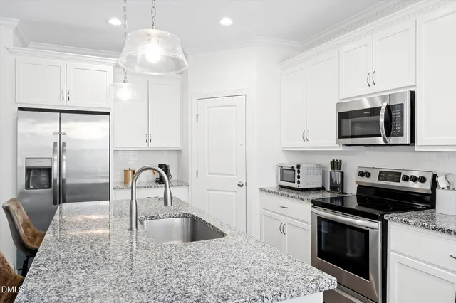 a kitchen with kitchen island granite countertop a sink stainless steel appliances and white cabinets