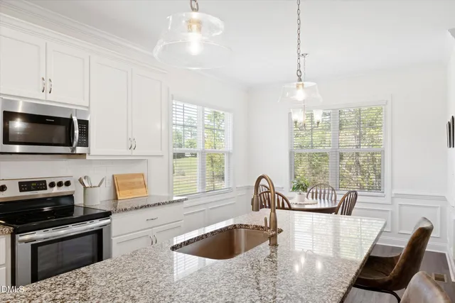 a kitchen with stainless steel appliances granite countertop a stove a sink a microwave and dining table