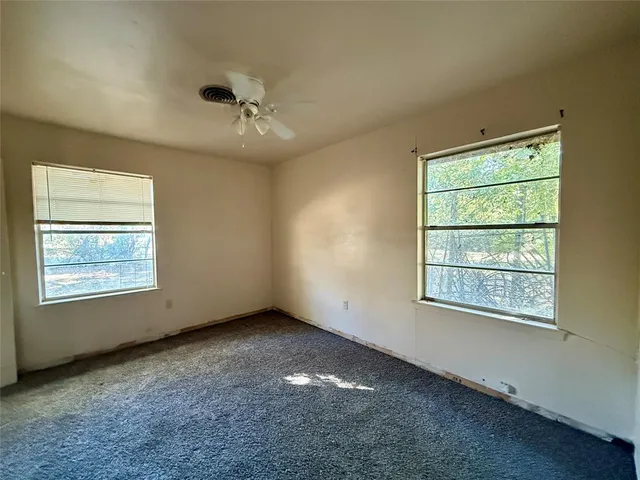 an empty room with a window and a ceiling fan