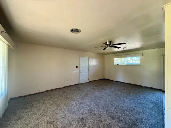 an empty room with a ceiling fan and window