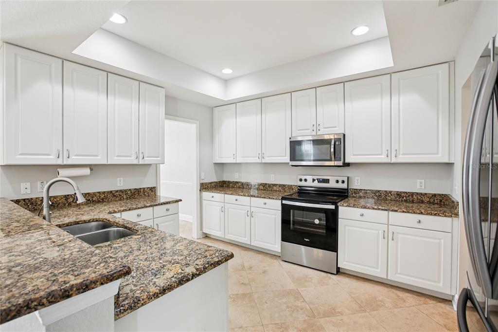 270 Cleveland Avenue Southwest Largo, FL 33770 - Photo 29 of 35 a kitchen with granite countertop white cabinets and stainless steel appliances