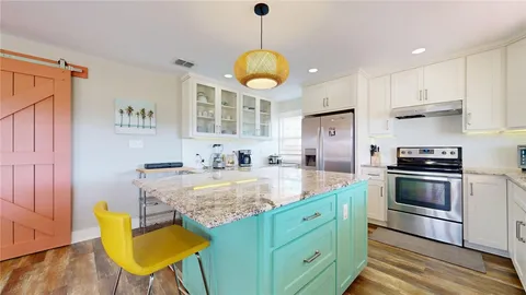 a kitchen with stainless steel appliances granite countertop a sink a stove a refrigerator cabinets and dining table