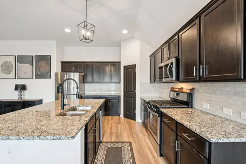 a kitchen with stainless steel appliances granite countertop a sink stove and refrigerator