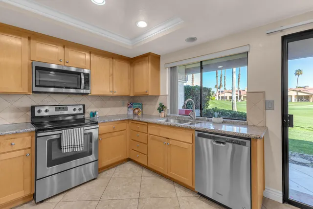 a kitchen with granite countertop wooden cabinets stainless steel appliances and a window