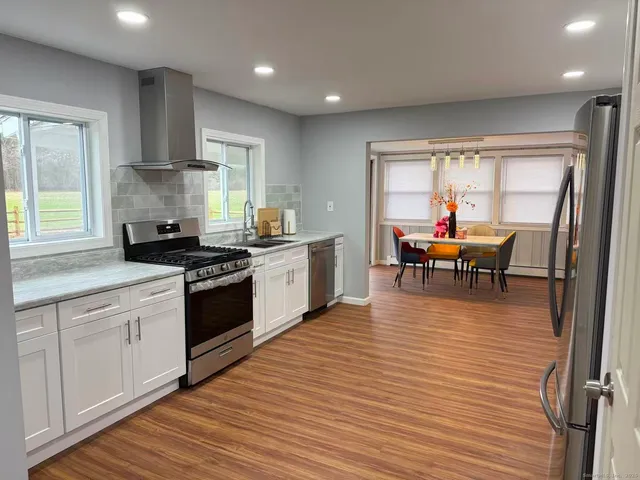 a kitchen with stainless steel appliances granite countertop wooden floors a stove and a window