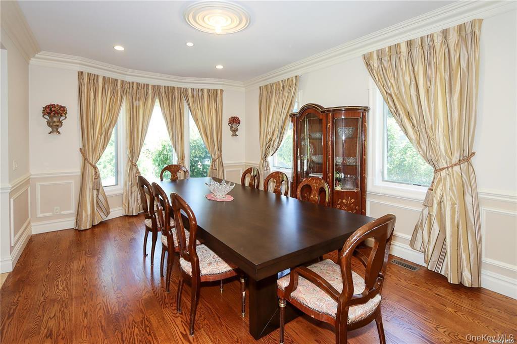 24 Steamboat Road Great Neck, NY 11024 - Photo 13 of 28 Dining area with plenty of natural light, a decorative wall, a wainscoted wall, wood finished floors, and crown molding