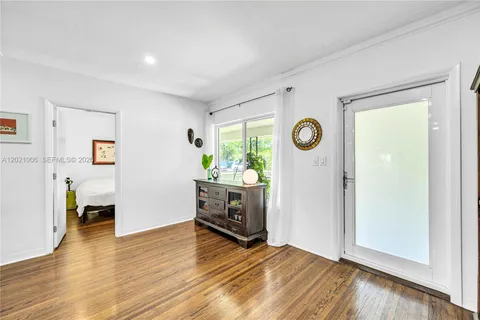 a view of an empty room with kitchen and window