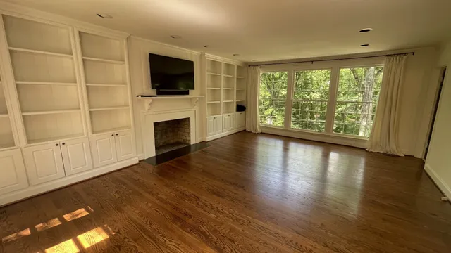 a view of an empty room with a window and wooden floor