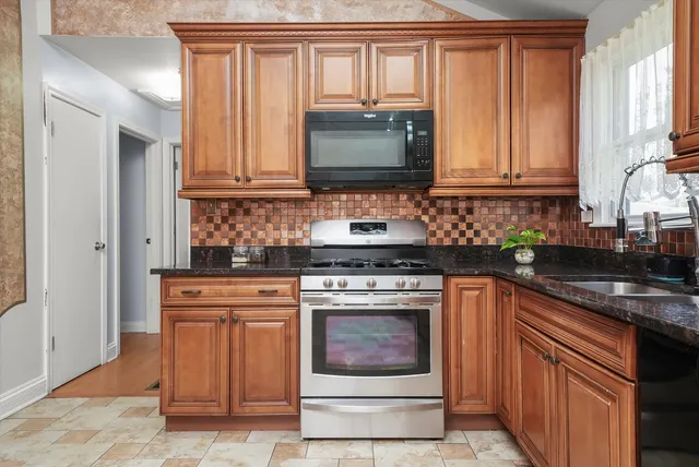 a kitchen with granite countertop a stove top oven cabinetry a sink and a microwave