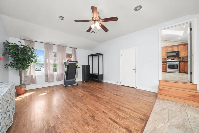 a view of empty room with wooden floor and ceiling fan