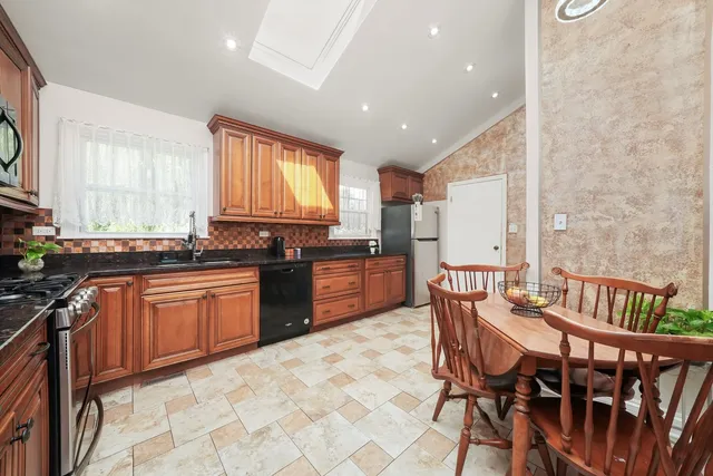 a kitchen with stainless steel appliances granite countertop a stove top oven a sink a dining table and chairs