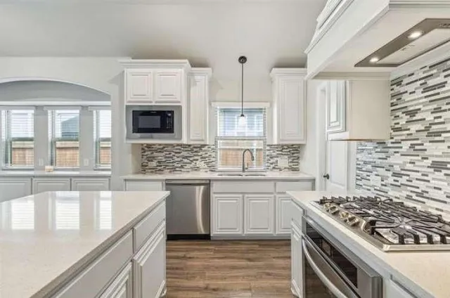 a kitchen with stainless steel appliances a stove a sink and a microwave