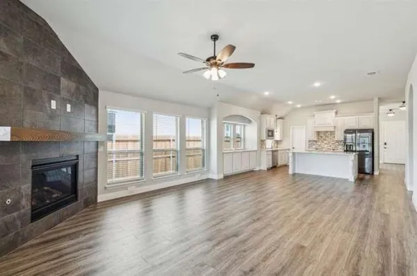 a view of an empty room with wooden floor fireplace and a window