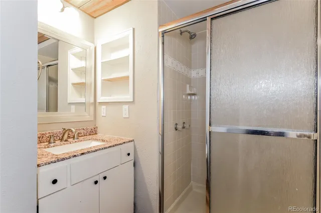 a bathroom with a granite countertop shower sink vanity and mirror