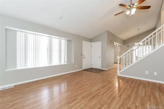 a view of an empty room with wooden floor and a window