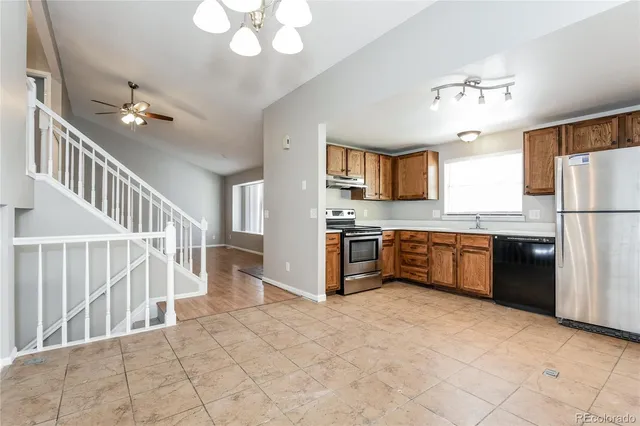 a kitchen with stainless steel appliances a refrigerator a stove a sink dishwasher a dining table and chairs