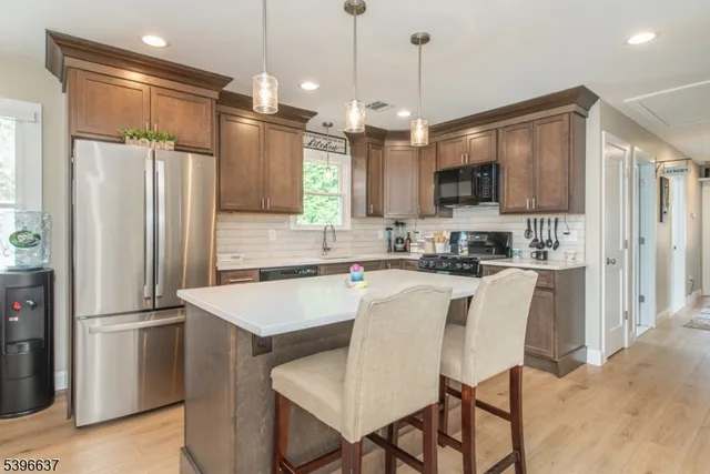 a kitchen with kitchen island a refrigerator a stove a microwave oven a sink and a dining table with white cabinets