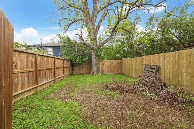 a view of backyard with wooden fence and large trees