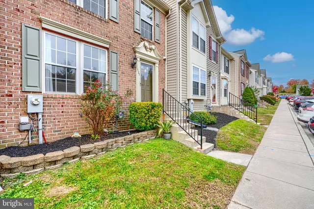 a view of a brick house with a yard and plants