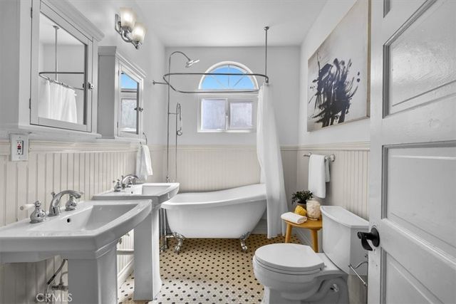 a bathroom with a sink a toilet a mirror a vanity and bathtub